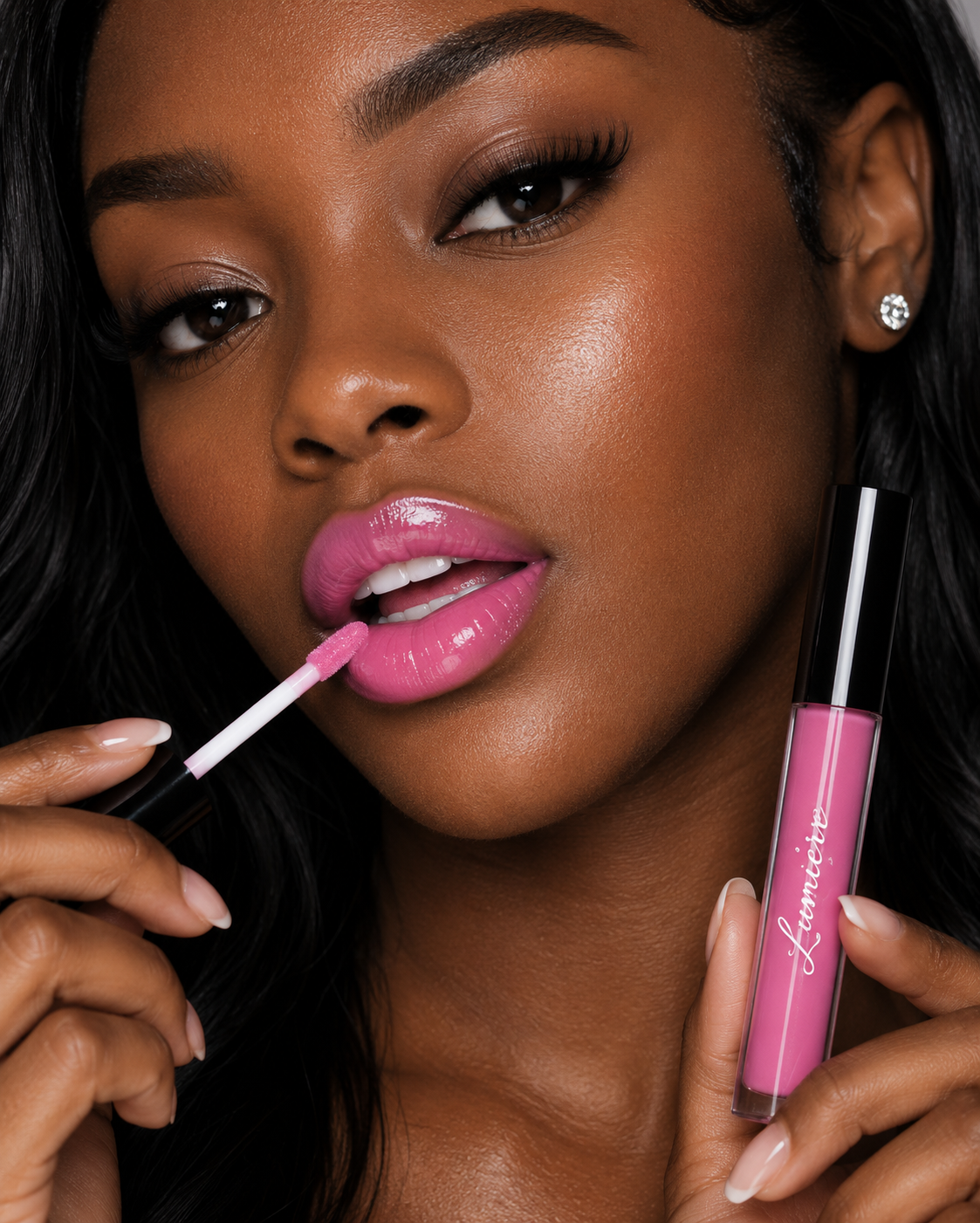 Model applying Lumière Pink Petal lip gloss